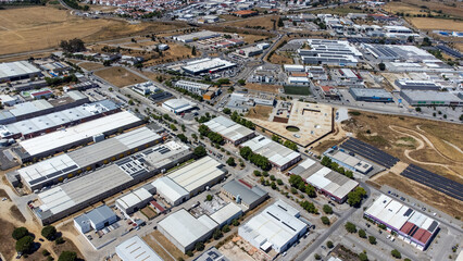 Fototapeta premium Aerial view of Évora's Industrial and Technological Park showcasing modern facilities, green spaces, and infrastructure against a backdrop of the historic city's landscape.