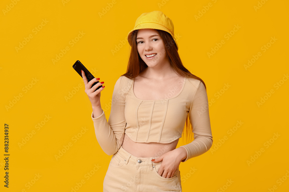 Wall mural pretty young girl with mobile phone on yellow background