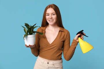 Pretty young woman with houseplant and water sprayer on blue background