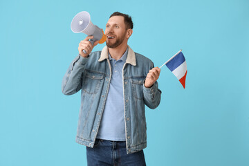 Young man with flag of France and megaphone on blue background