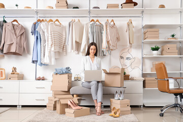 Female seller with laptop taking online order in clothing store