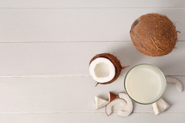 Glass of tasty fresh coconut milk on white wooden background
