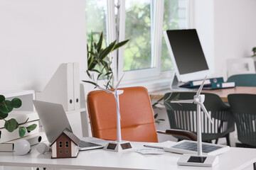 Engineer's workplace with wind turbine models and laptop in office