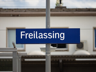 Obraz premium Freilassing train station sign in Bavaria. Location signage of the travel destination near the border to Austria. Public transportation in the region Berchtesgadener Land.