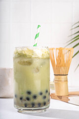Green matcha boba bubble tea with tapioca pearl. Trendy asian cold iced drink with dark tapioca balls and non-dairy whipped creamed, copy space