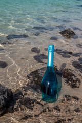 Turquoise bottle of sparkling wine on the beach, Spain