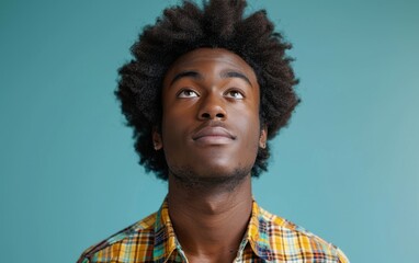 Fototapeta premium A man with a plaid shirt and dreadlocks looking up at the camera. Scene is contemplative and introspective