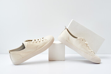 Pair of stylish sneakers on white background with geometric podium
