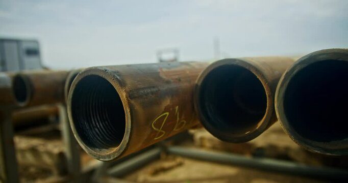 Metal rusty pipes lying in a row outdoors. Materials prepared for the arrangement of drilling equipment at the site.