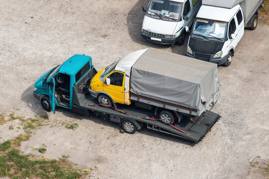 Small truck in inoperable condition on a tow truck in a parking lot
