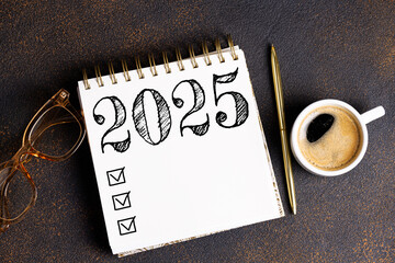 New year resolutions 2025 on desk. 2025 goals list with notebook, coffee cup, plant on desk....