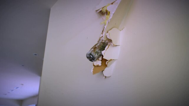Sledge hammer comer through a hole in a wall