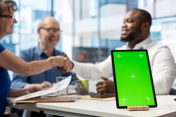 Financial advisor shakes hands with old people after choosing a retirement plan to secure their pension, tablet with green screen. Banker talking to elderly couple about life insurance.