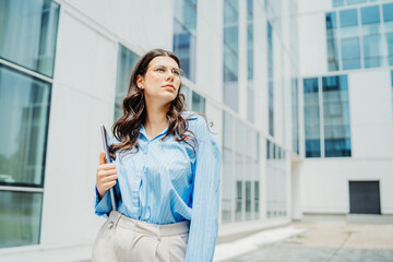Fototapeta premium One beautiful young successful business woman going to work at business office modern building while holding laptop and wearing glasses 