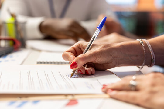 Elderly woman giving her signature on retirement plan contract, choosing the suitable pension option with life insurance policy to secure the future income and family expenses. Close up.