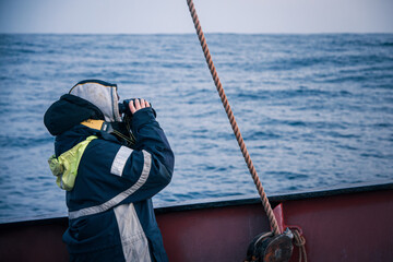 Person on Ship Deck Using Binoculars