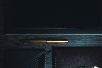 Workplace. Notebook with pen and tablet on a wooden table. Strict style