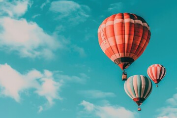 Naklejka premium Three hot air balloons drift gracefully through the clouds on a bright, sunny day