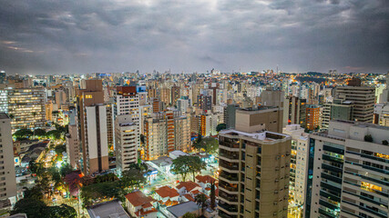 Vista a&eacute;rea noturna do bairro Cambu&iacute; na cidade de Campinas, interior de S&atilde;o Paulo. V&aacute;rios pr&eacute;dios residenciais e luzes da cidade com c&eacute;u nublado.