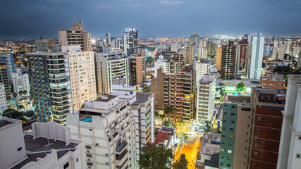 Obraz premium Vista aérea noturna do bairro Cambuí na cidade de Campinas, interior de São Paulo. Vários prédios residenciais e luzes da cidade com céu nublado.