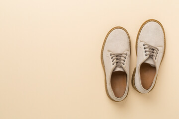 Beige suede shoes on color background, top view