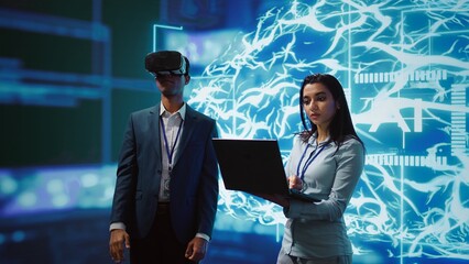 Technician wearing VR headset looks at hologram of artificial intelligence human brain simulation,...
