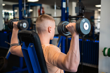 Bodybuilder lifts dumbbells during a workout in a gym