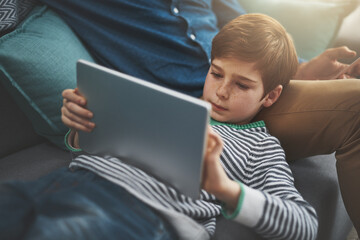 Happy, tablet and parent with child on sofa for online streaming, playing games and internet. Family, home and dad with young boy on digital tech for watching movies, cartoons and videos for bonding