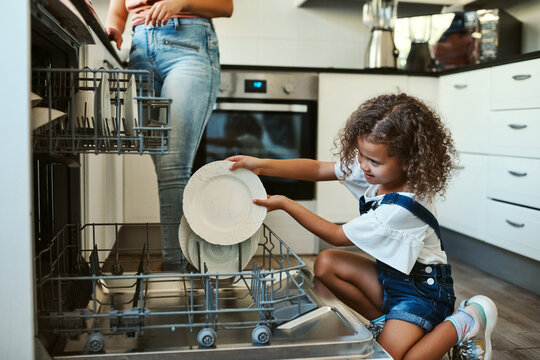 Dish washer, parent and child washing plate in home for chores, responsibility or helping hand in kitchen. Machine, care and girl in house cleaning or packing for development, learning or hygiene