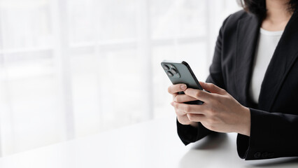 Businesswoman using a smartphone in a modern office, staying connected and productive. Professional female executive or entrepreneur in a corporate workspace