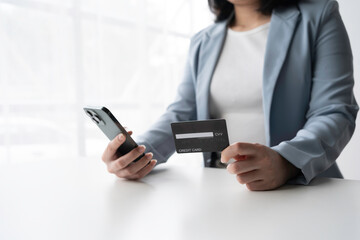 Businesswoman making an online payment on a smartphone, holding a credit card, online shopping and digital banking concept