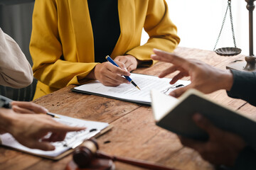 Lawyer is explaining contract details to client at a meeting in the office. They are discussing...
