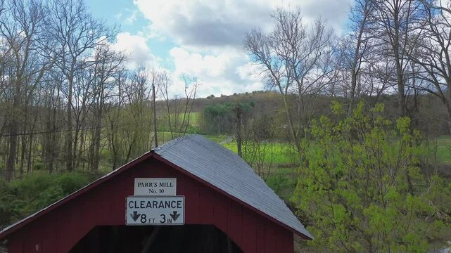 Parr's Mill covered bridge near Catawissa, PA. Rising flyover shot that begins at a bridge portal and flies along the roof line, showing a field beyond. Shot in early Spring.