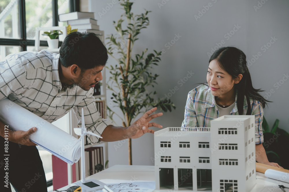 Wall mural two architects discussing sustainable building project, examining scale model and blueprints, brains