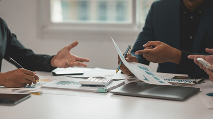 Business people are having a meeting, analyzing financial documents with charts and using a calculator to calculate some numbers