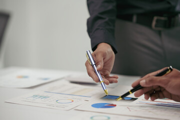 Two business professionals deeply engaged in a meeting, analyzing financial data and pointing at...