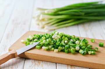 cutting board with fresh green onion on table, selective focus.