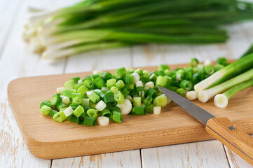 Slicing fresh spring onions on a cutting board , selective focus.