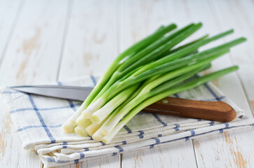 Fresh spring onions or scallions on a white table, selective focus.