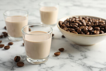Coffee cream liqueur in glasses and beans on white marble table