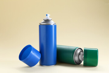 Two spray paint cans on beige background