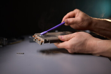 A technician is skillfully repairing a computer GPU fan with precision tools in a workshop