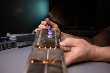 A technician is skillfully repairing a computer GPU fan with precision tools in a workshop