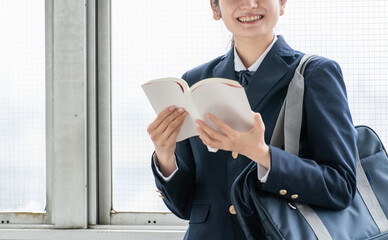 本・小説・漫画・教科書・参考書を読む笑顔の高校生
