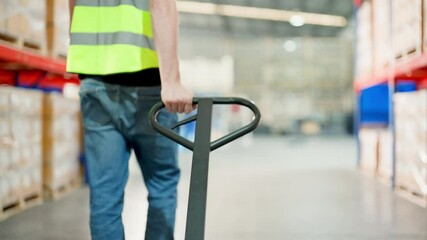 Warehouse worker walking and pull forklift truck in warehouse. Man engineer working in storehouse