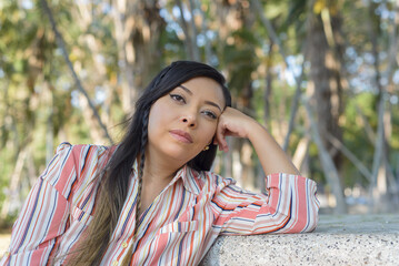 Woman seated in a public park with an attitude of preoccupation, pensive.