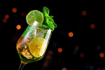 Popular summer cocktail drink with sparkling wine, elderflower syrup, soda, lime, mint and ice in wine glass, dark background