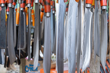 rows of machete swords with wooden handles in a traditional sharp weapons souvenir shop....