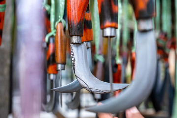 Karambit knife, a typical traditional Minangkabau silat weapon from West Sumatra hanging in a traditional weapons souvenir shop. Wallpaper background with traditional weapons theme
