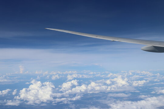 Aerial View of Urban Landscape with Airplane Wing Under Clear Blue Sky and Scattered Clouds